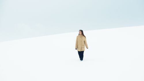 Free Woman strolling alone in a vast snowy field, wearing a brown coat during winter. Stock Photo