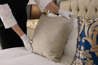 Woman Fixing Pillows on a Bed
