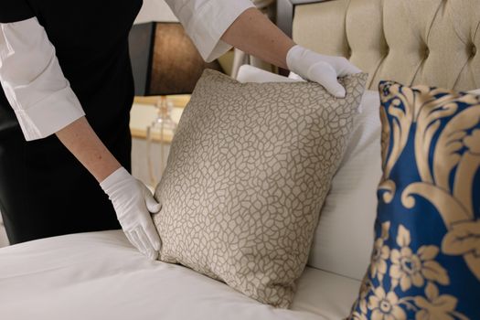 Woman Fixing Pillows on a Bed
