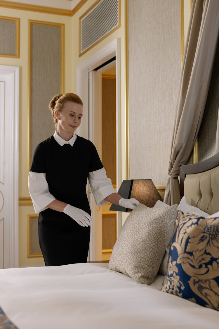 Woman Fixing A Pillow On Bed