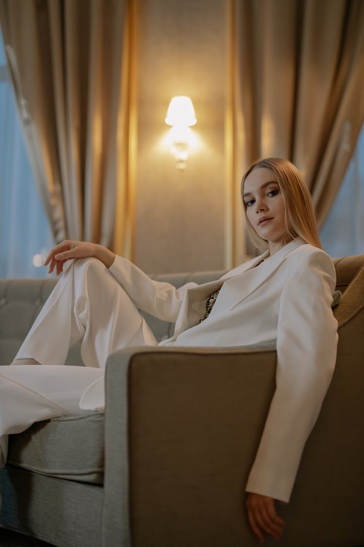 Woman In White Suit Sitting On A Couch