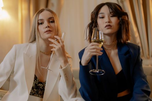 Two stylish women enjoying champagne indoors, showcasing elegance and luxury lifestyle.