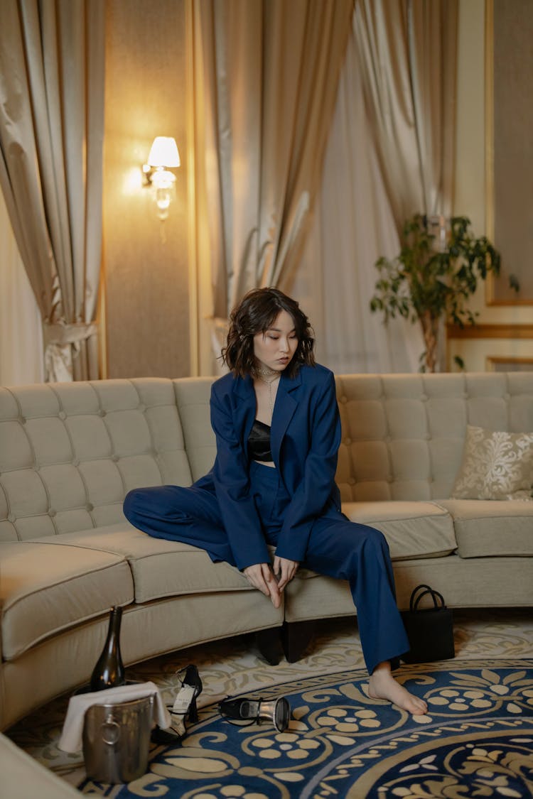 Woman In Blue Suit Sitting On A Sofa