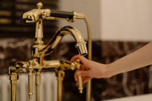 Free Close-Up Shot of a Person Touching a Gold Faucet Stock Photo