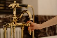 Close-Up Shot of a Person Touching a Gold Faucet