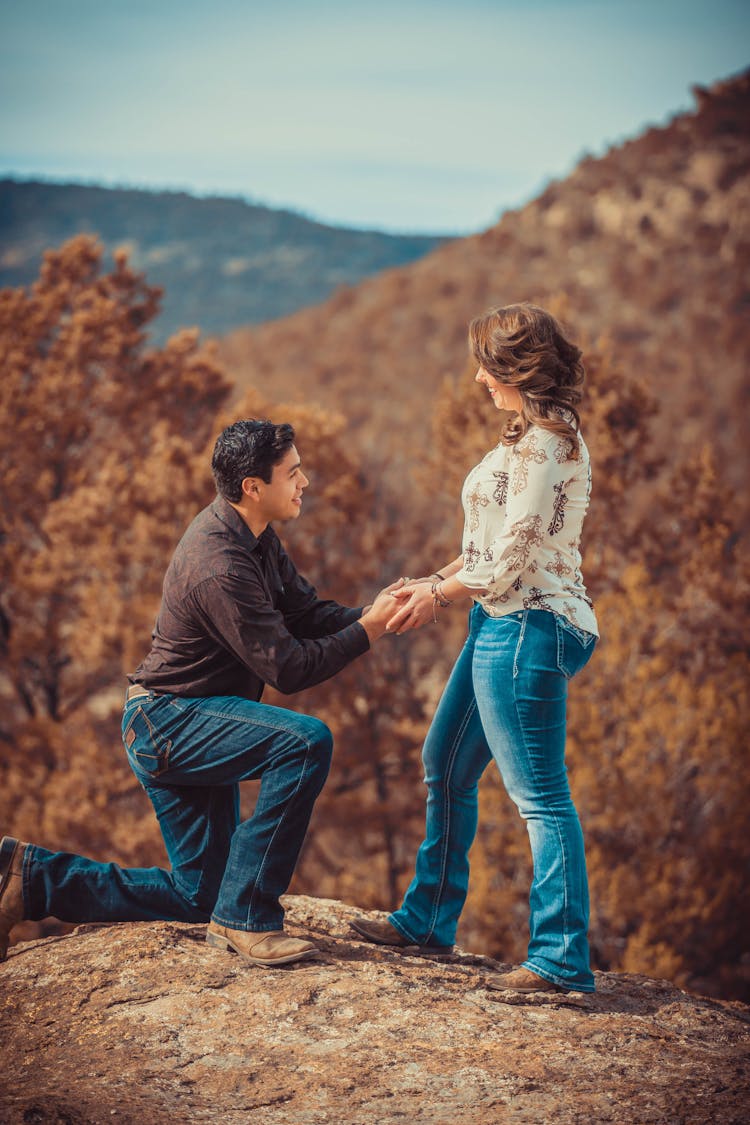 A Man Kneeling While Proposing To Her Partner