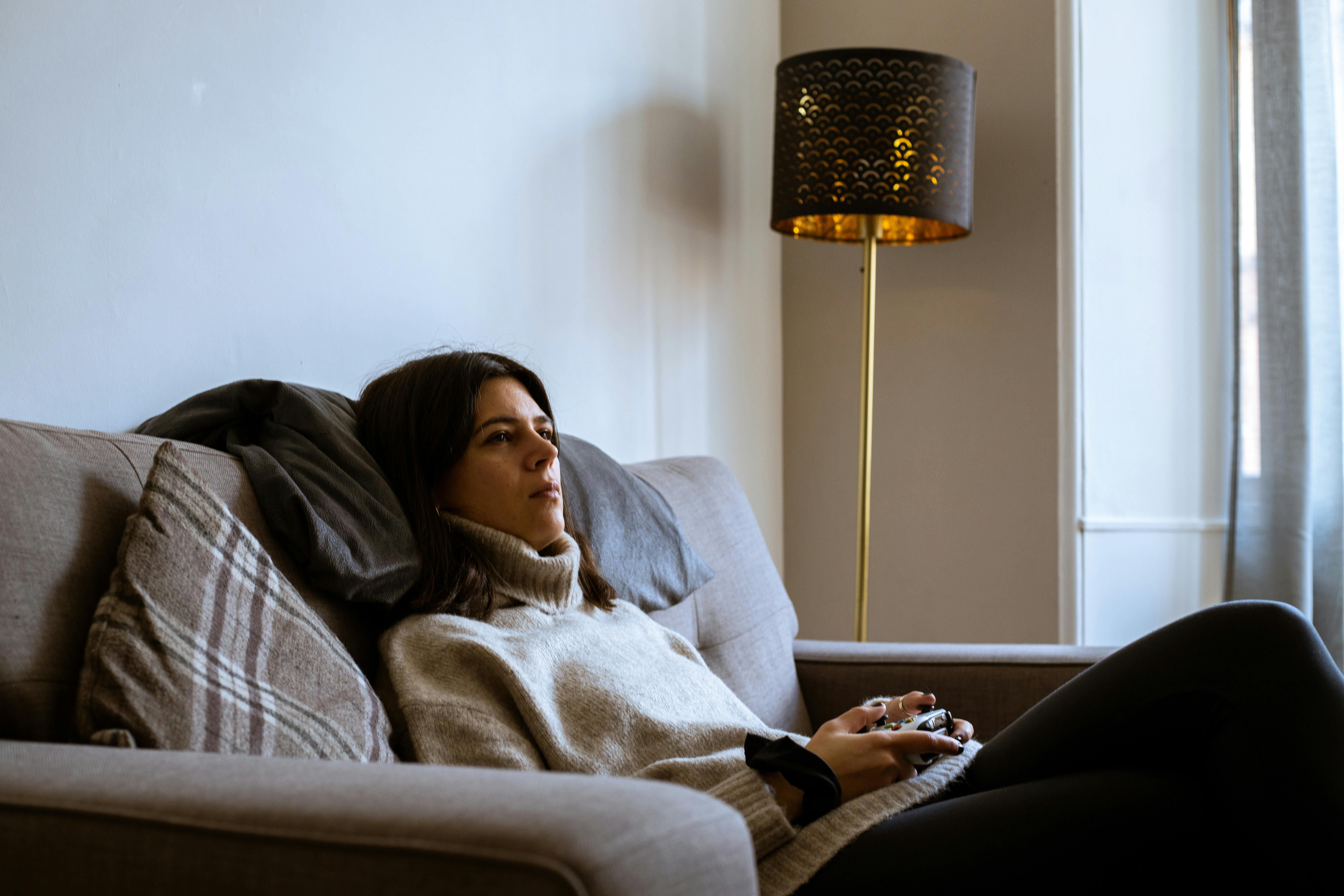 a woman sitting on a couch while wearing a turtle neck sweater