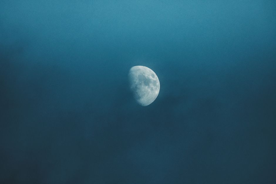 Waxing white moon with gray spots illuminating on foggy sky at bright night