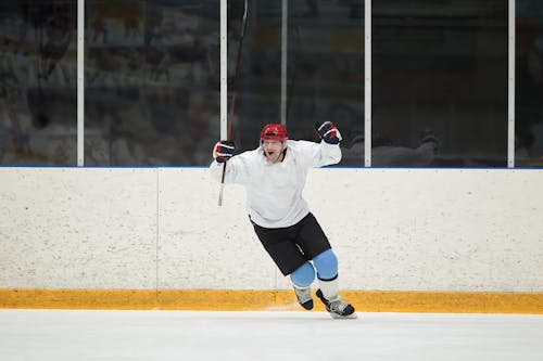 Hombre En Camisa Blanca De Manga Larga Y Pantalones Cortos Negros Jugando Hockey Sobre Hielo