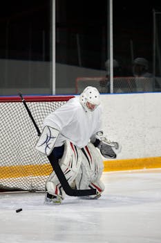 Professional hockey goalie in action, guarding the net during an ice hockey game indoors.