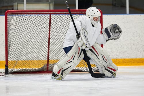 A Goaltender Wearing a Full Gear while Protecting It's Goal Post