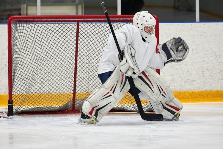 A Goaltender Wearing A Full Gear While Protecting It's Goal Post