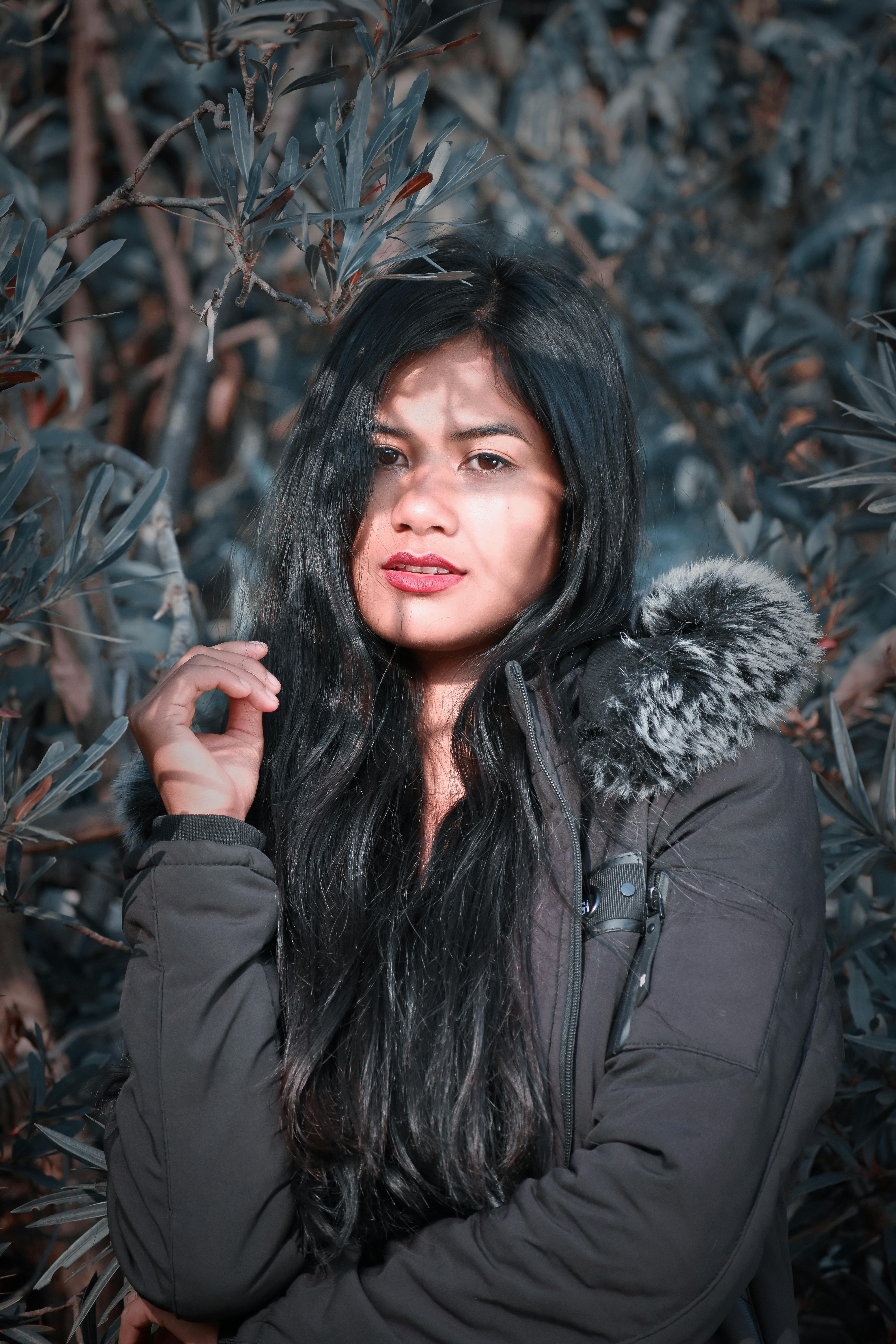 A captivating portrait of a woman wearing a winter jacket with fur hood, set against a natural backdrop.