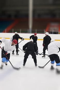 A group of ice hockey players practicing drills on an indoor rink, focusing on teamwork and skill development.