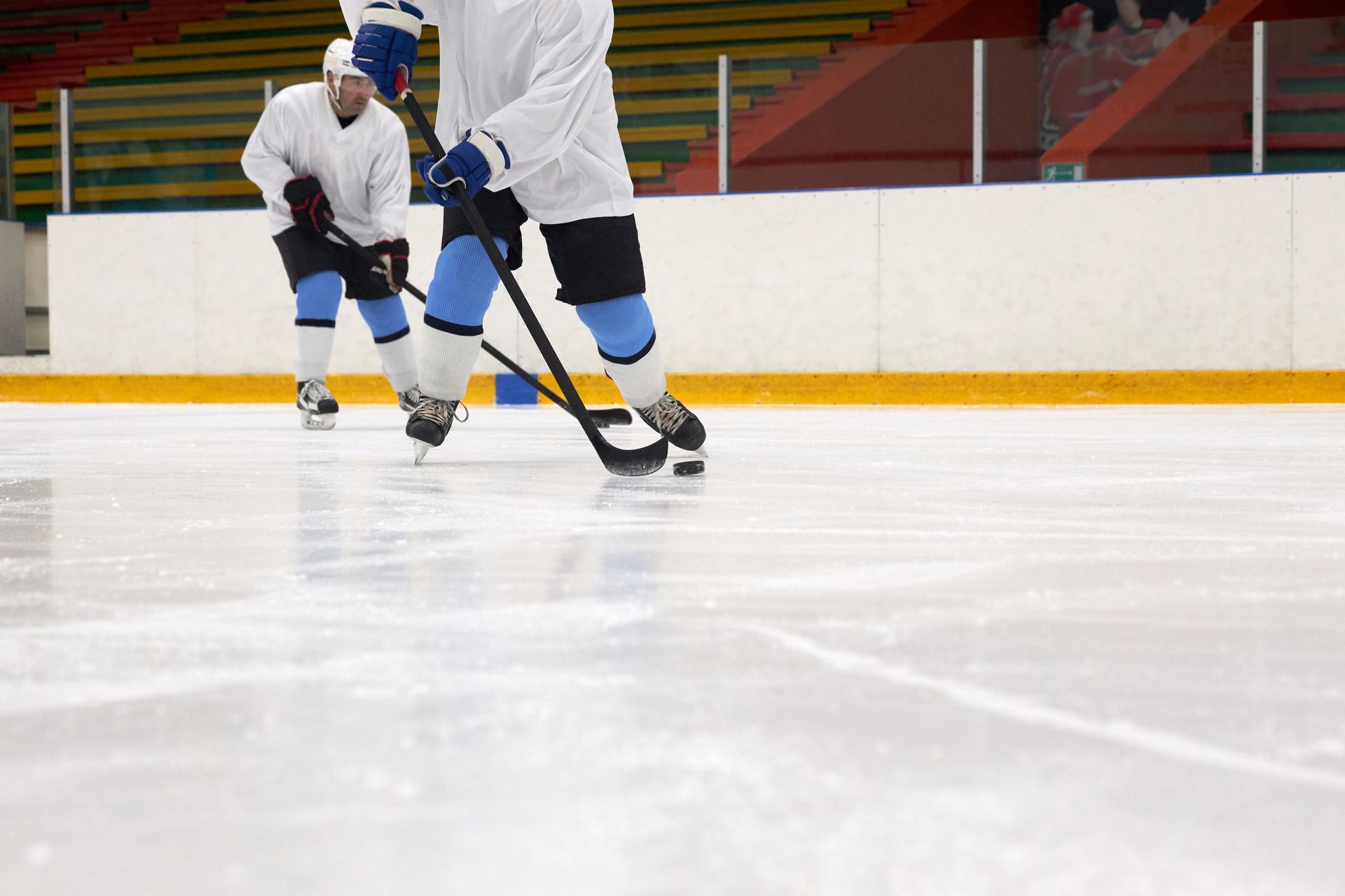 Players actively competing in an ice hockey game inside a rink with visible audience.