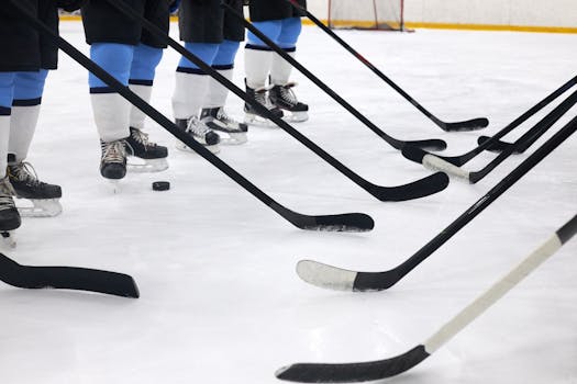 Close-up of hockey players on ice with sticks ready for a faceoff.