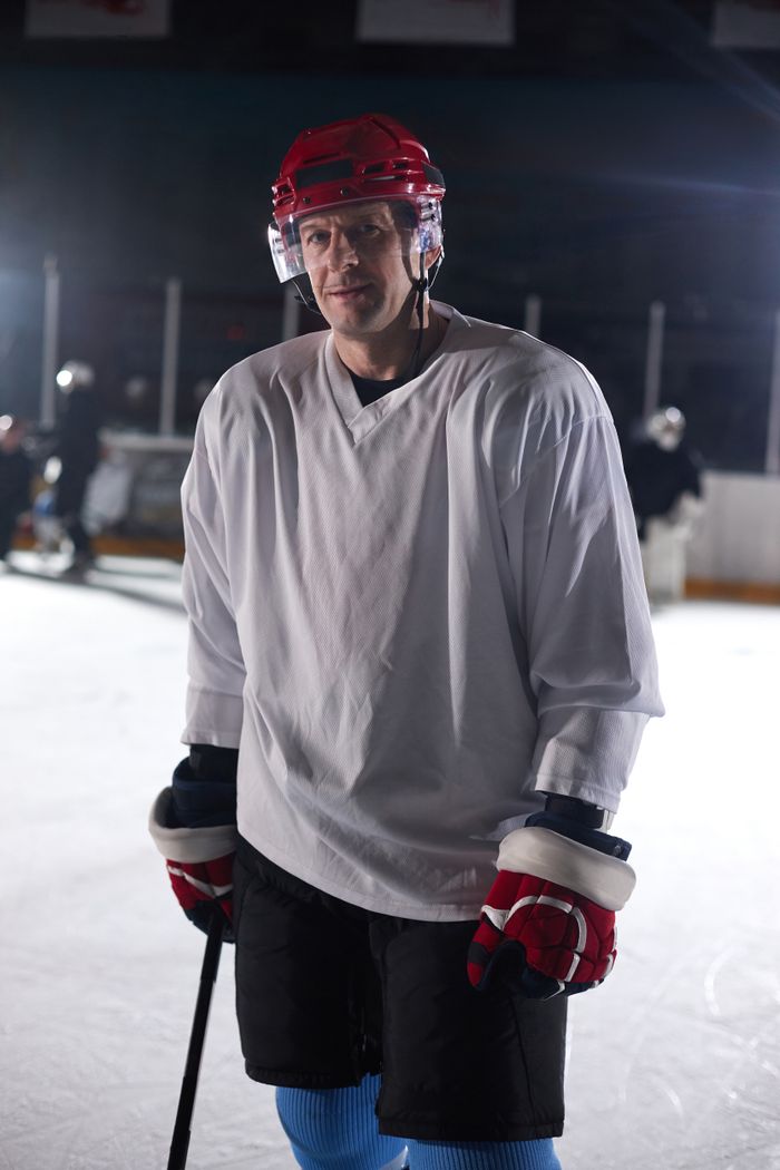 Young hockey player in helmet and gloves looking toward the camera