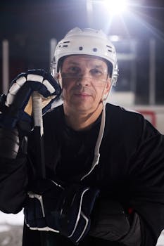 Portrait of a professional hockey player with gear and helmet on an ice rink, ready for action.