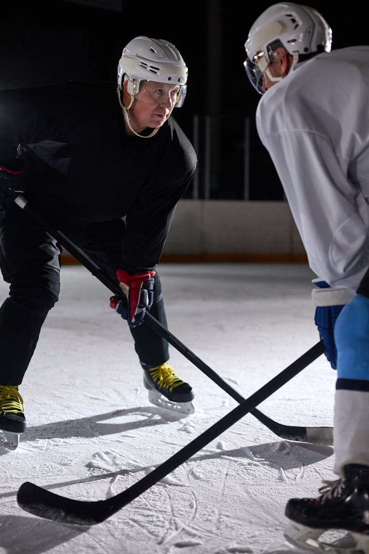 Two People Standing On An Ice Rink While Holding Hockey Sticks