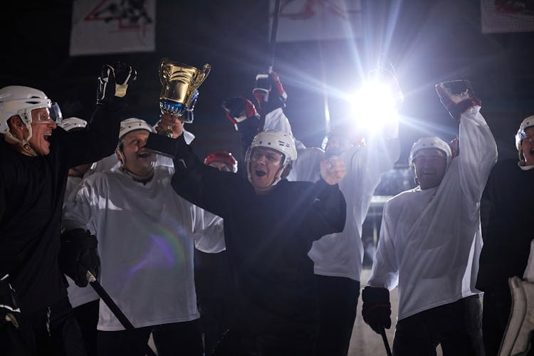 A Group Of Men Celebrating Their Win On A Hockey Competition