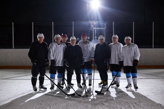 A team of male ice hockey players posing on the rink under bright lights.