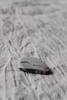 A detailed view of a single pebble on a textured fabric, creating an interesting contrast.