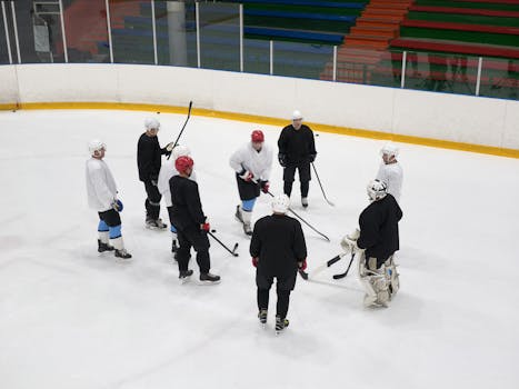 A team of male ice hockey players gathers on the rink for practice, showcasing teamwork and sportsmanship.