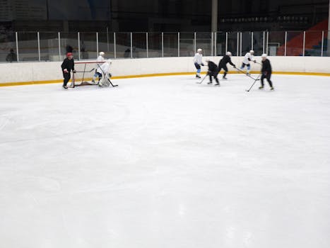 Dynamic hockey match indoors with players skating and maneuvering on an ice rink.