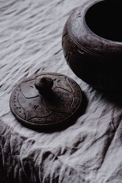 Free Close-up of an antique carved clay container with lid on textured cloth surface. Stock Photo