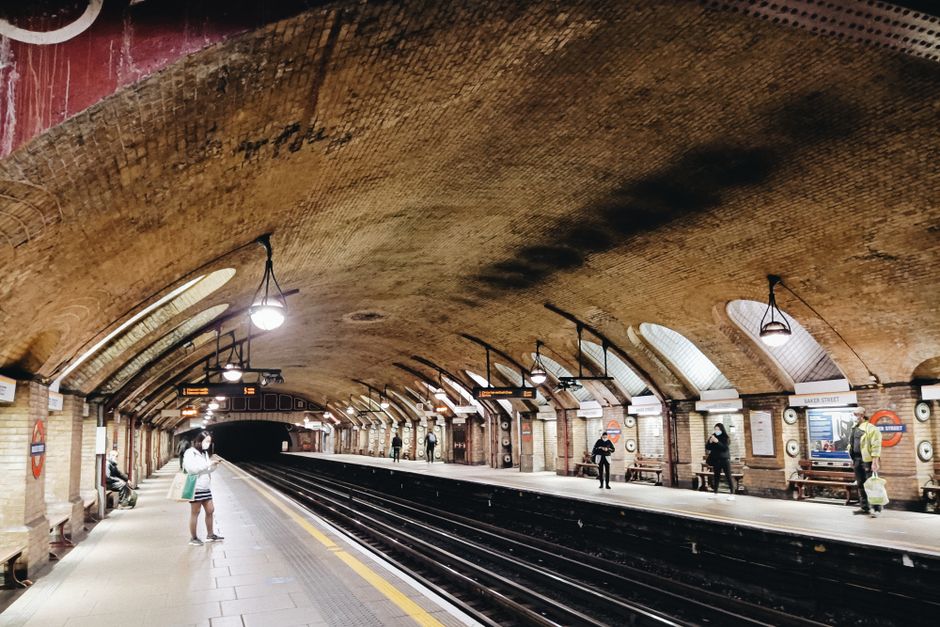 An iconic underground station with vintage arched ceilings and commuters waiting on the platform.