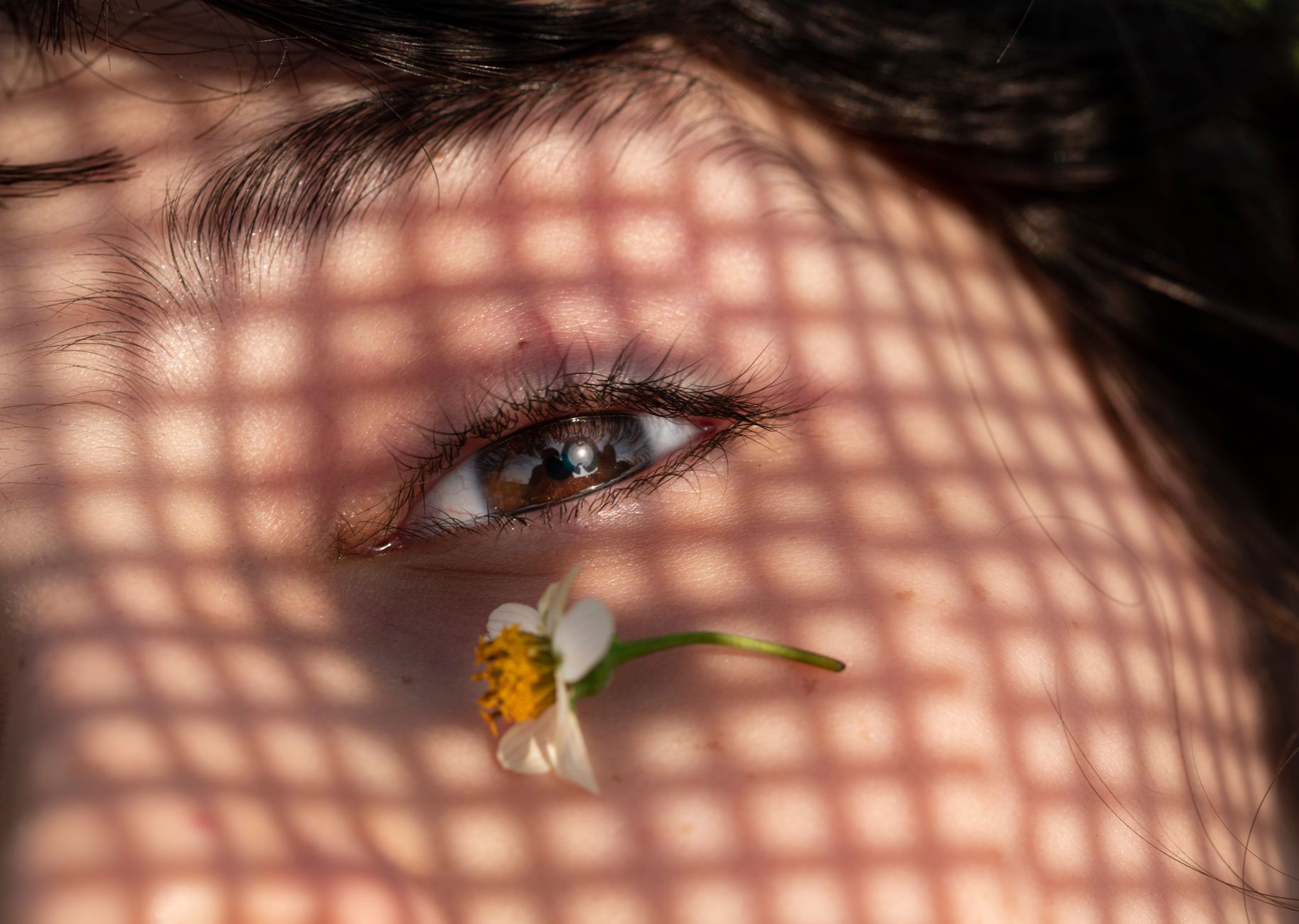 Macro close-up of a human eye with patterned shadows falling across the skin