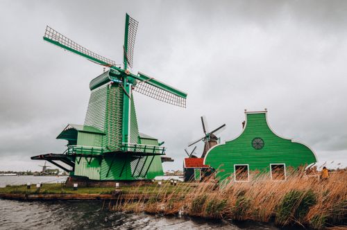 Free Scenic view of traditional green windmills in Kinderdijk, Netherlands, against a cloudy sky. Stock Photo