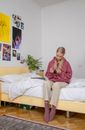 A Young Woman Looking at a pack of Condoms While Sitting on a Bed