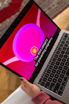 Close-up of a laptop showing a contraception video with subtitles.