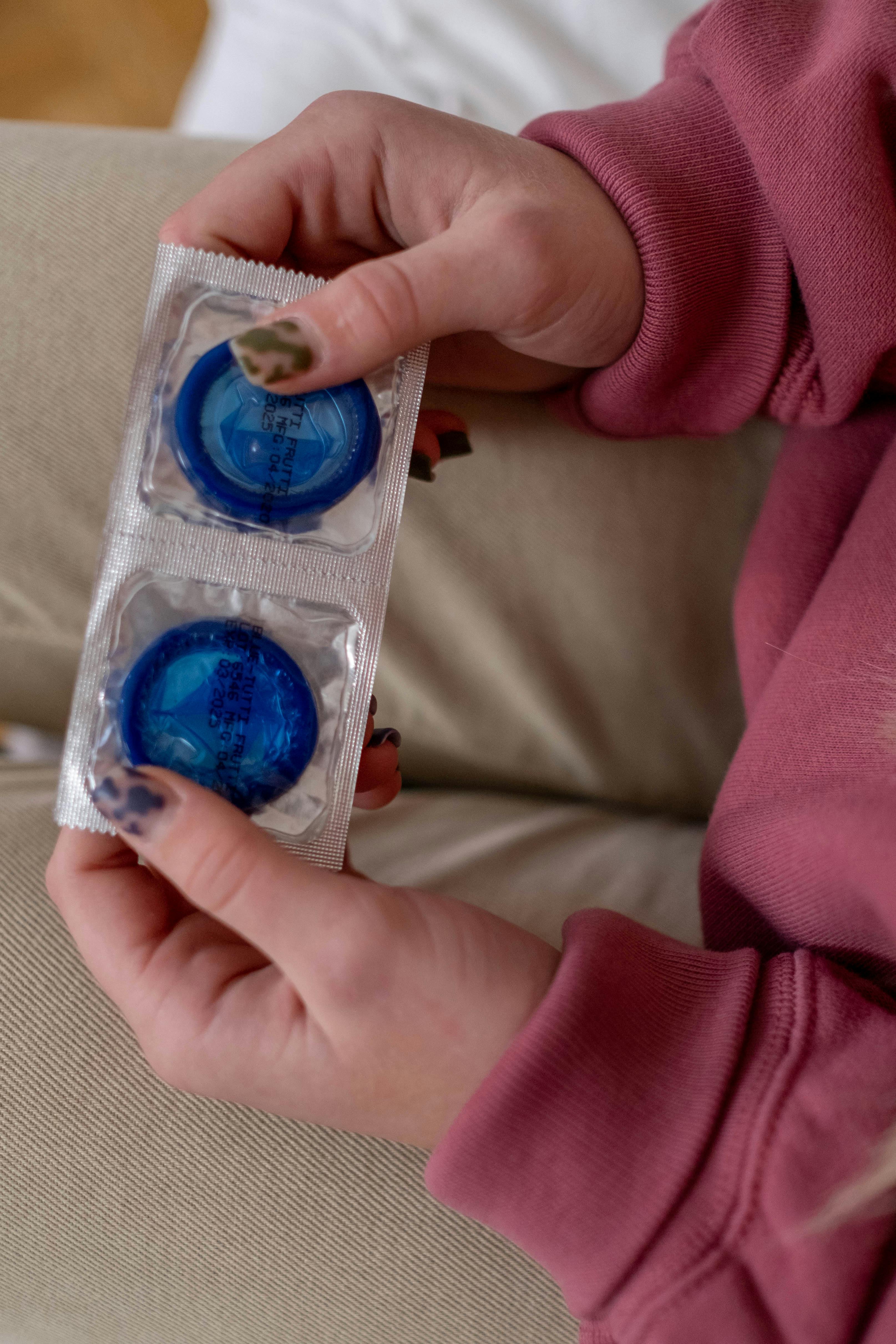 person holding blue condoms