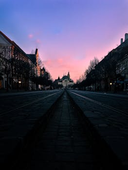 Beautiful sunset casting pastel hues over a deserted street leading to a cathedral.