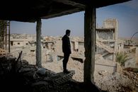 Full body side view of anonymous male standing in demolished house above remains of ruined buildings on street in poor district