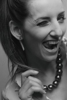 Black and white portrait of a woman expressing joy with a bold necklace.