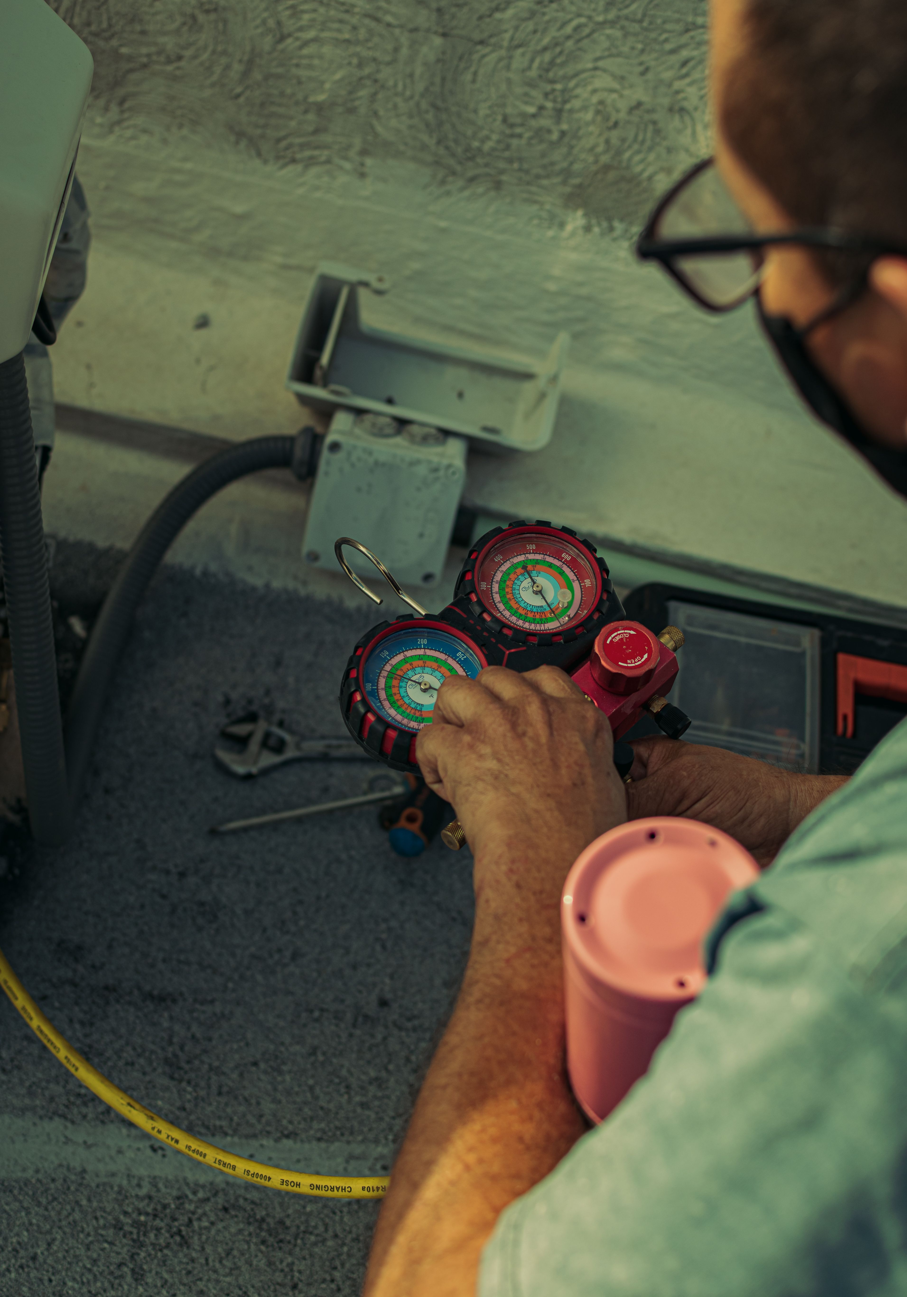 Manifold gauges in hand at an outdoor condensing unit