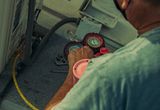 Technician working on an outdoor unit with gauges and tools