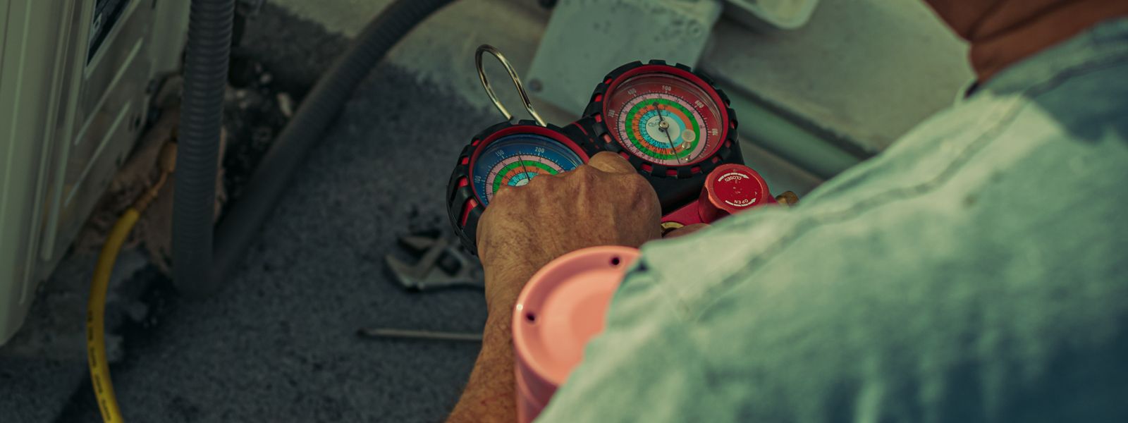 Technician working on an outdoor unit with gauges and tools