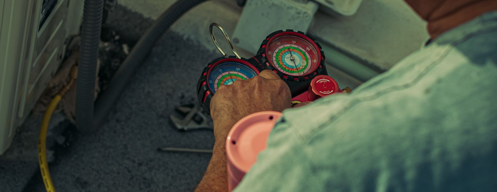 Technician working on an outdoor unit with gauges and tools