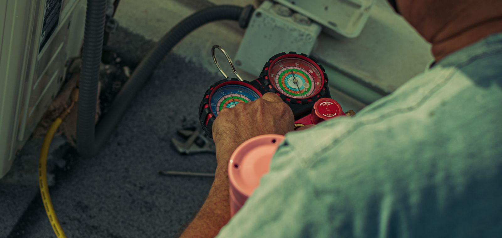 Technician working on an outdoor unit with gauges and tools