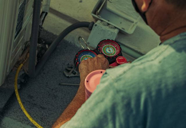 Technician working on an outdoor unit with gauges and tools