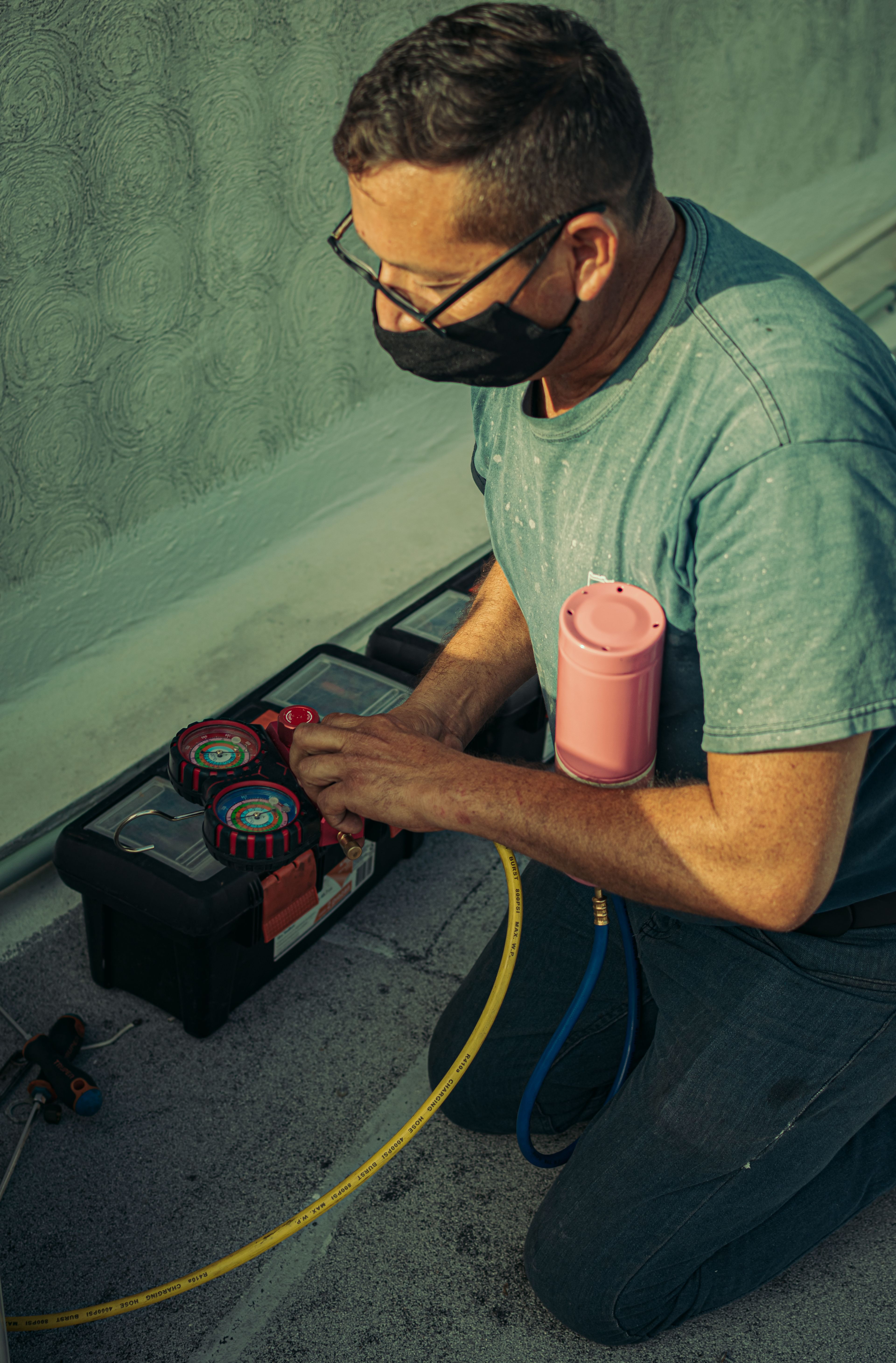 Technicien agenouillé réalisant l'entretien d'une installation de ventilation avec un outillage spécialisé