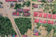 Overhead view of colorful roofs of residential buildings and lush green trees in flooded small village