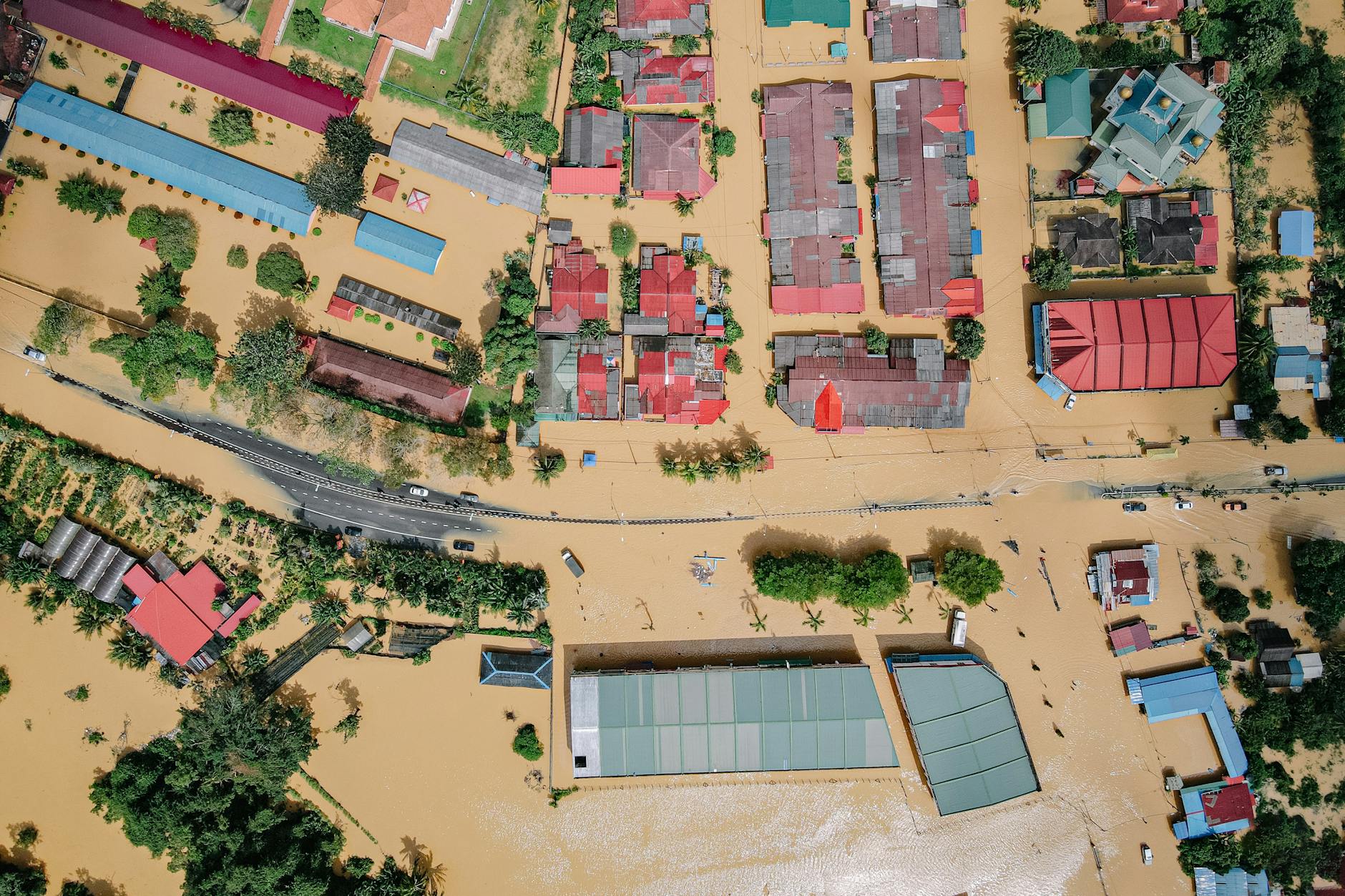 Photo by Pok Rie Aerial view showing significant flood damage in a residential neighborhood with inundated streets and homes.
