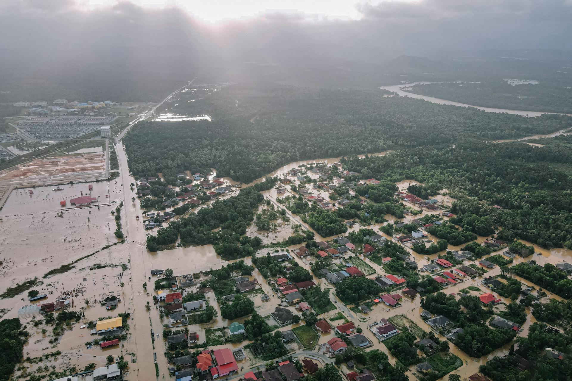 Aerial view of many residential houses and lush green trees in flooded small city