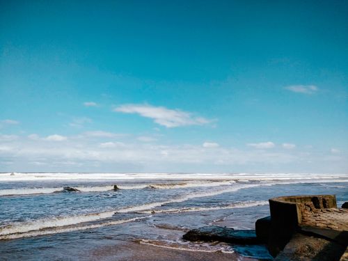 Free Peaceful beach scene with gentle waves under a clear blue sky. Stock Photo