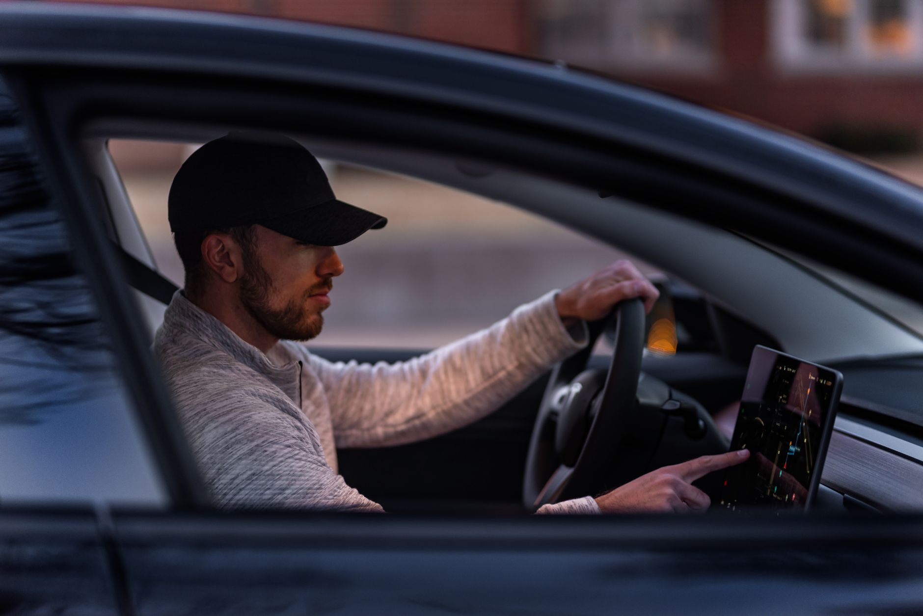 A man interacts with a touchscreen inside an electric car, driving through Dallas, TX.